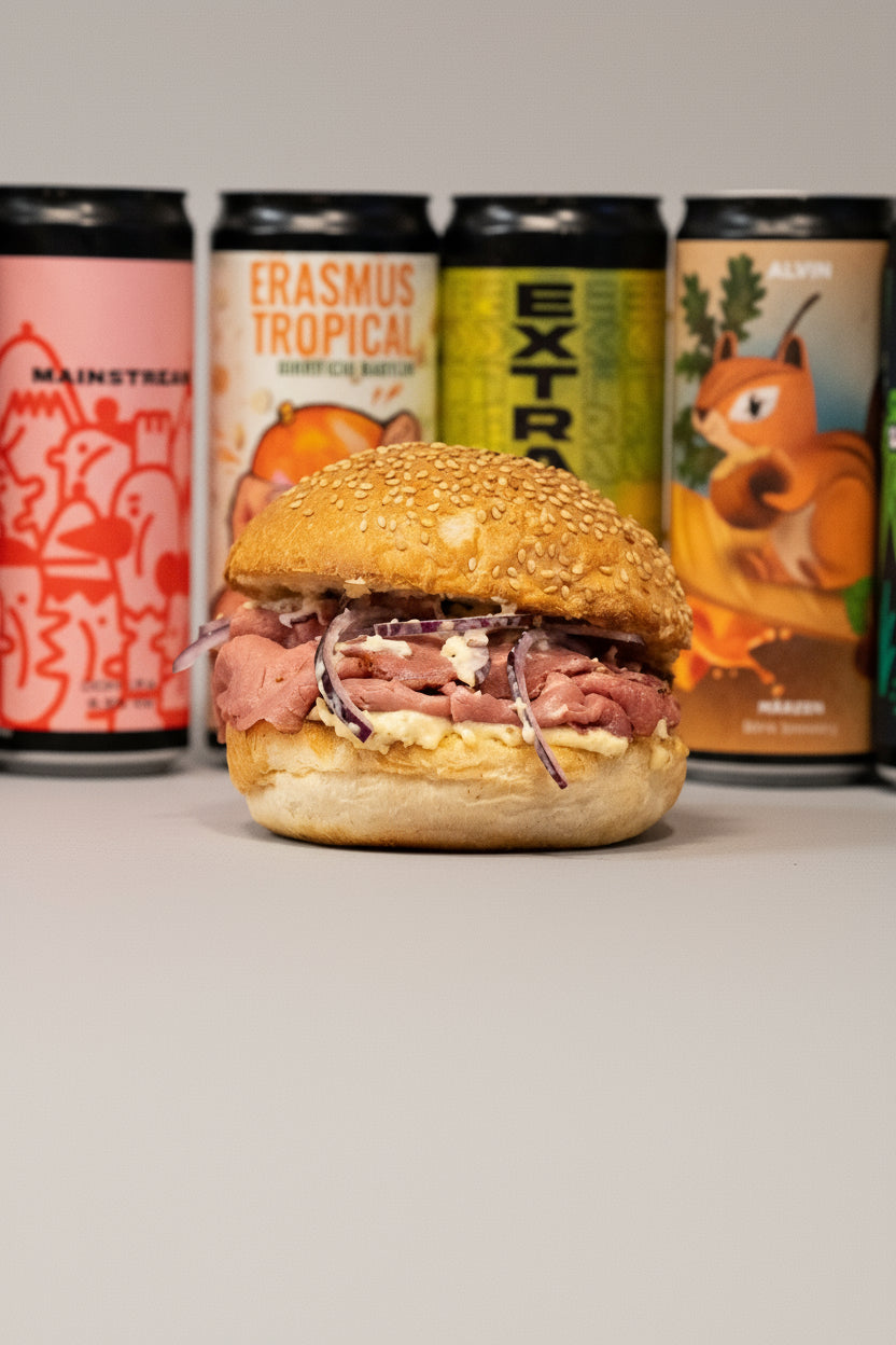 Burger on a red and white striped surface with beer cans in the background